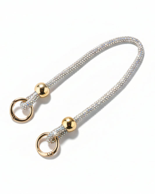 A clear mobile phone case with a luxury rhinestone lanyard attached to it, featuring a sparkling strap and rhinestone clasps.