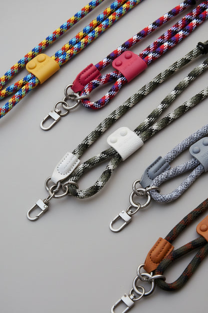 Collection of colorful braided lanyards with various attachments on a concrete surface.