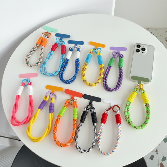 Colorful braided keychains on a white surface with a phone for scale.