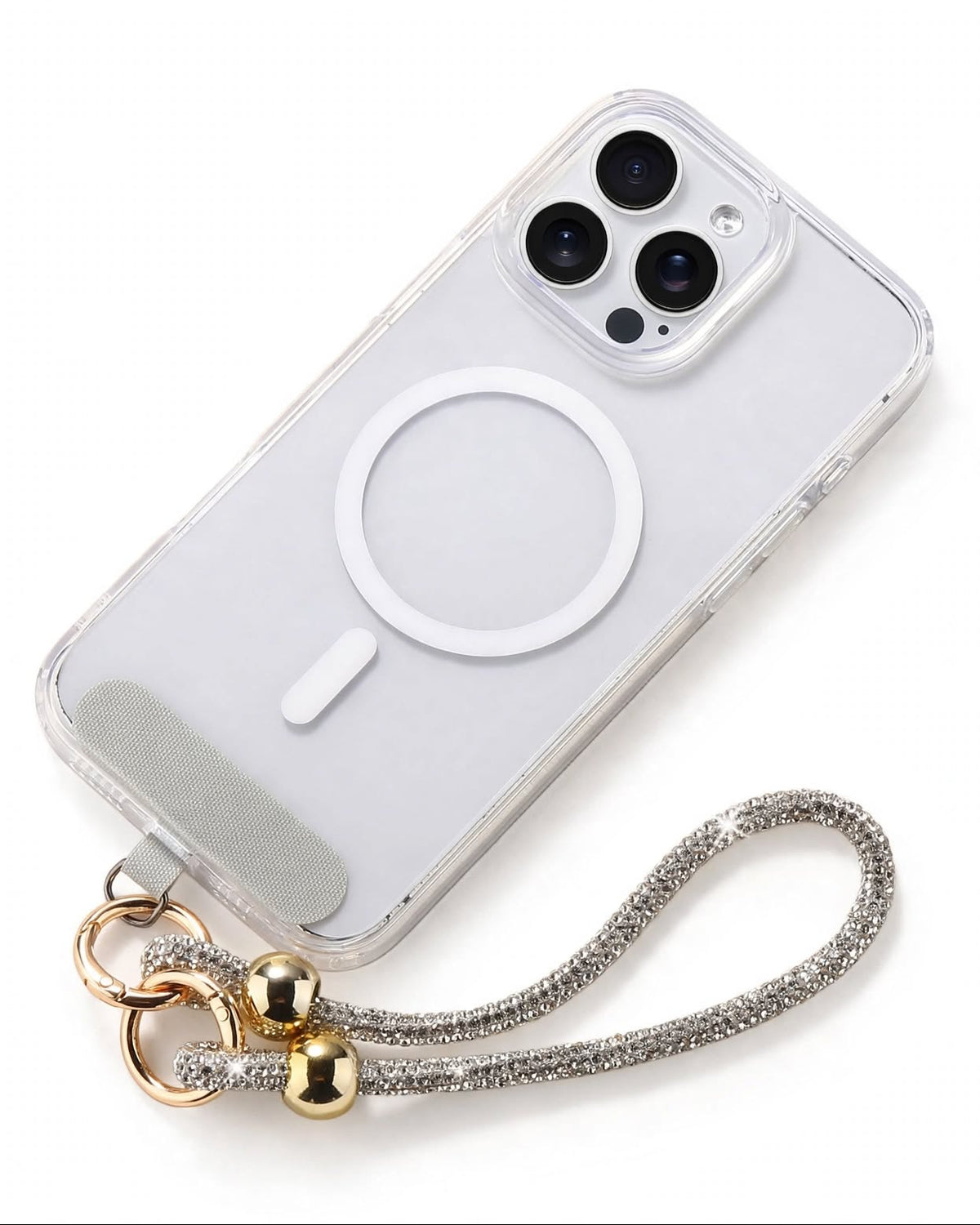 A clear protective phone case with a white MagSafe ring, shown on a white phone. The case is attached to a silver rhinestone-embellished wrist strap with gold-colored metal rings and beads, photographed on a clean white background.