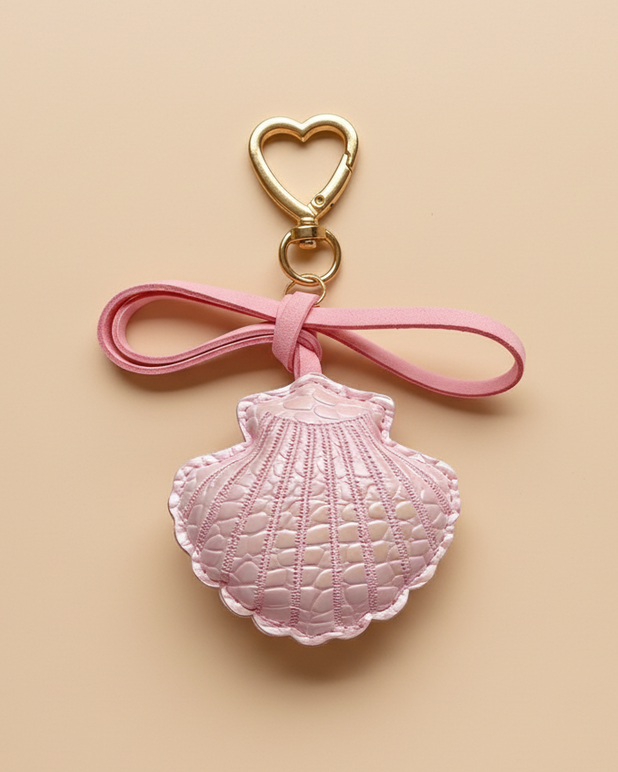 Pink shell keychain charm on a beige background
